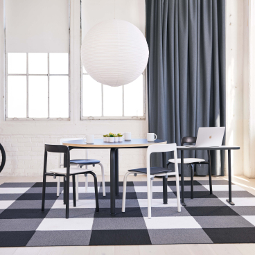 Modern workspace featuring Pearson Lloyd's Routes furniture with a stylish table, chairs, and a vibrant patterned rug.