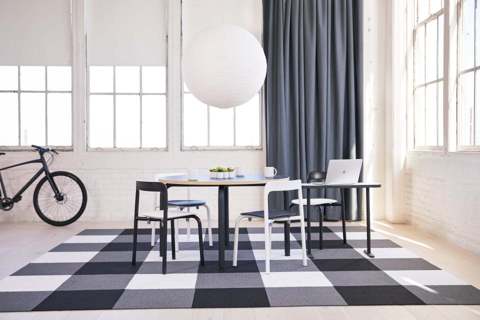 Modern workspace featuring Pearson Lloyd's Routes furniture with a stylish table, chairs, and a vibrant patterned rug.