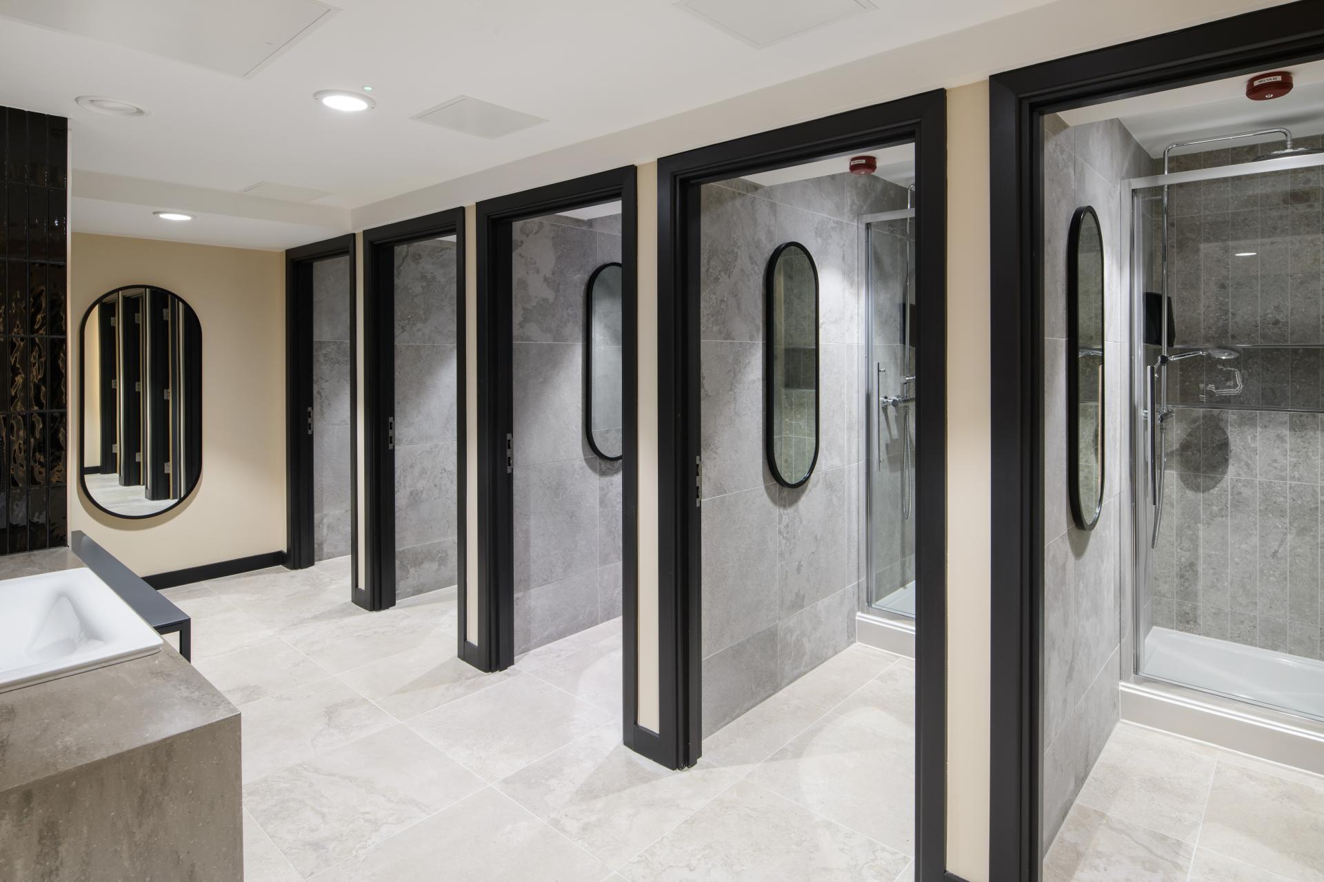 Modern restroom interior featuring stylish shower stalls and sleek design by SpaceInvader at One Piccadilly Gardens, Manchester.
