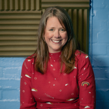 Helen Sheldon, director of RBA Acoustics, smiling in a studio with soundproofing, highlighting inclusivity and noise impact on wellbeing.