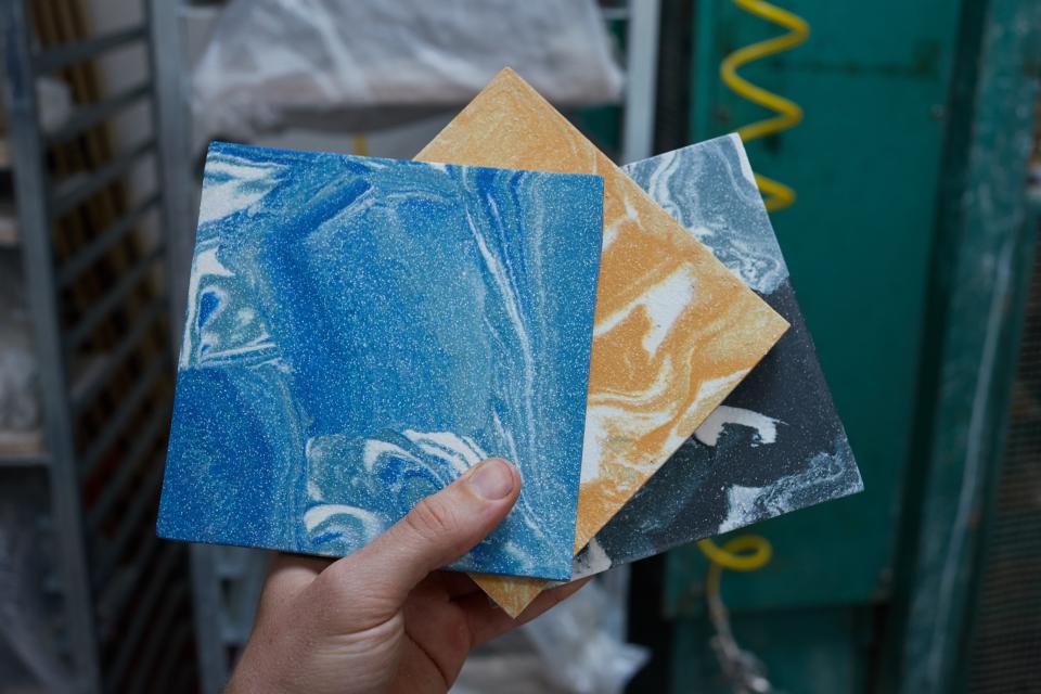 Hand holding three colorful encaustic tiles showcasing vibrant blue, yellow, and black marbled designs from Granby Workshop.