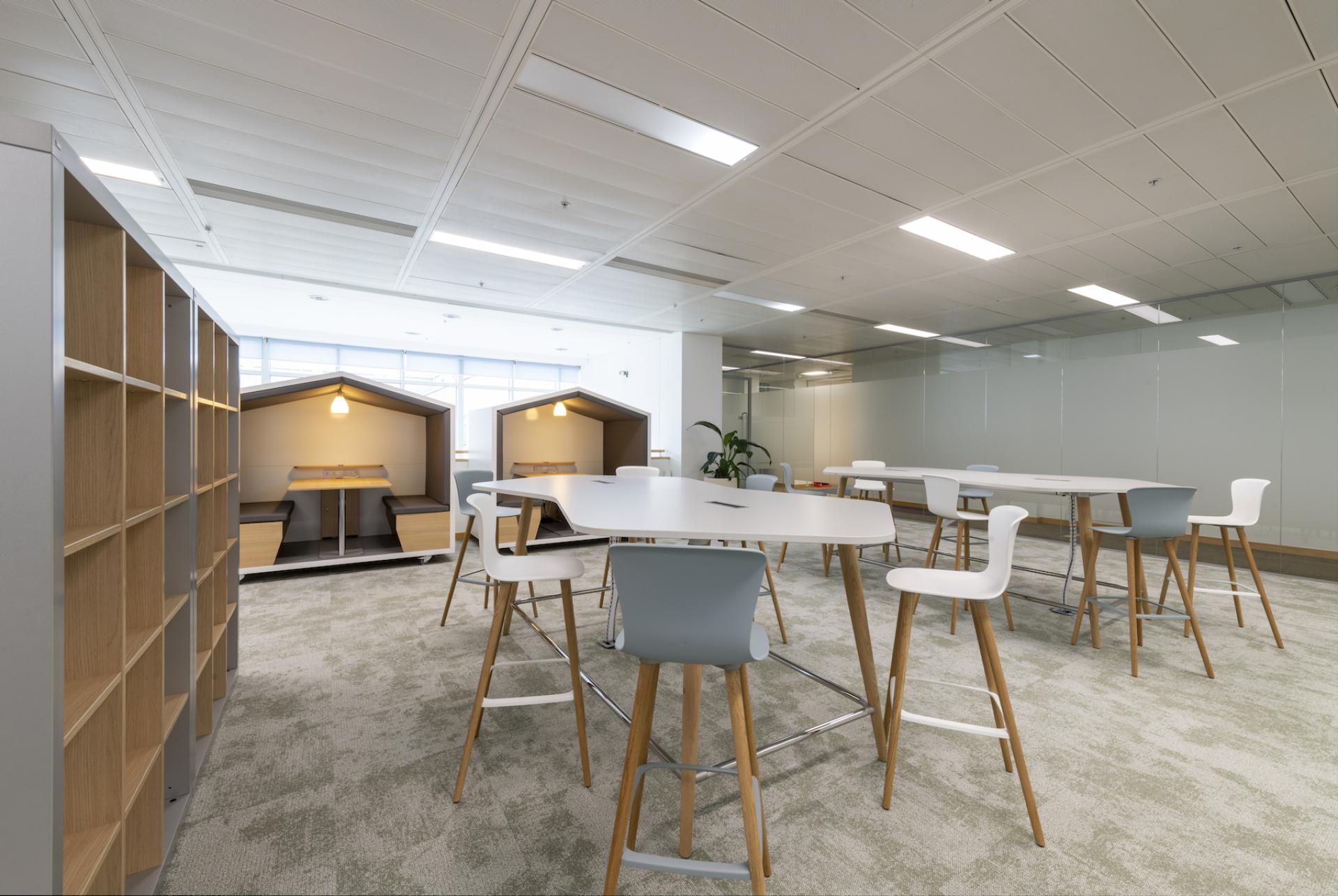 Modern office interior showcasing collaborative workspaces, stylish seating, and sustainable design elements in a vibrant colour palette.