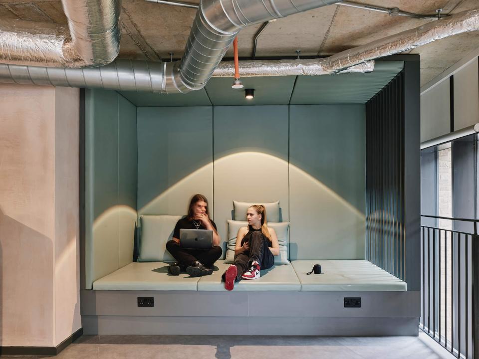 Modern student lounge area at The Tannery in Leicester, featuring two students engaging with a laptop.