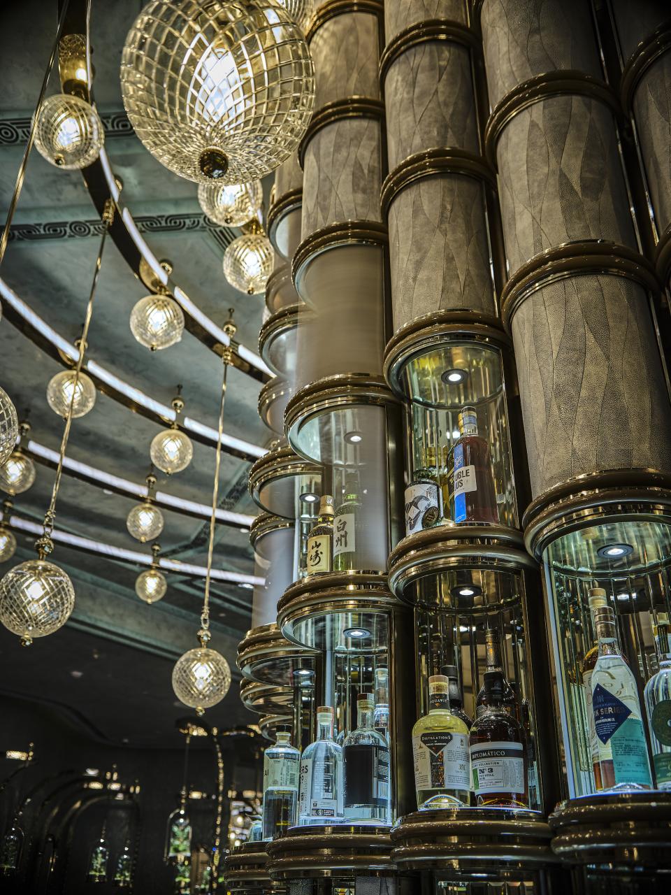 Elegant cocktail bar display featuring illuminated shelves with premium spirits and decorative pendant lights at Four Seasons Hong Kong.