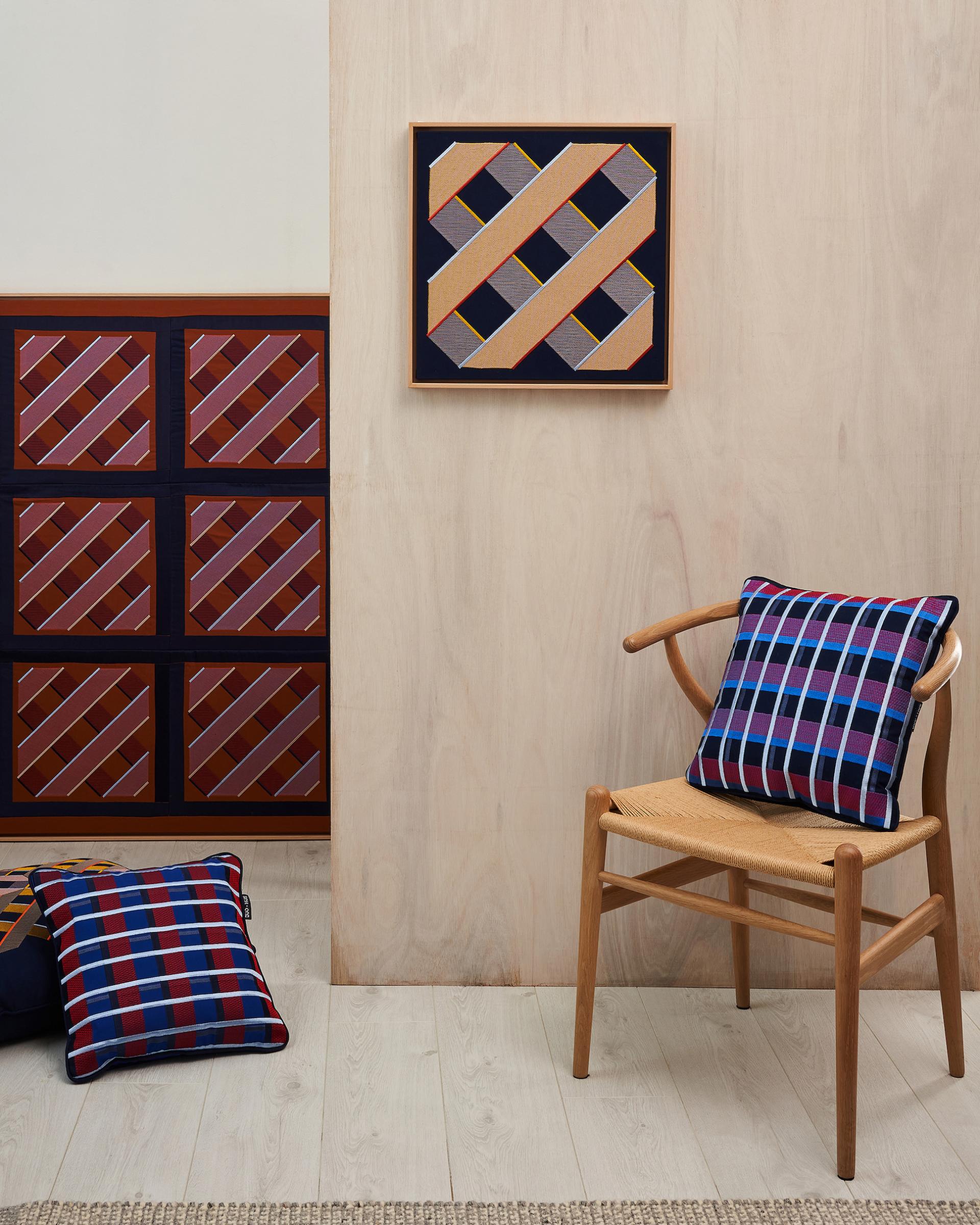 Dynamic digital embroidery patterns displayed on a wall, complemented by stylish embroidered cushions on a wooden chair.