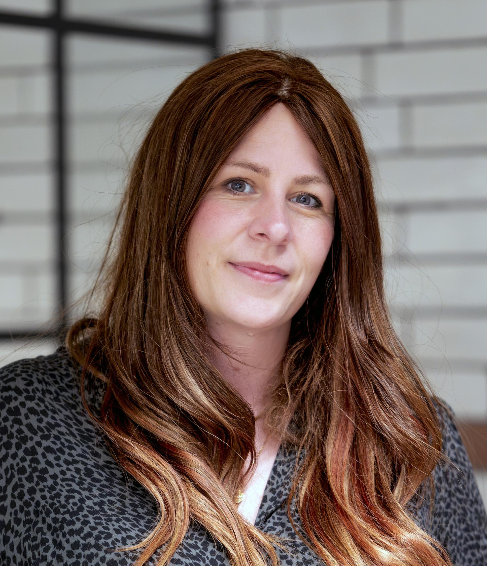 Woman with long brown hair and a patterned blouse, engaged in a discussion about Manchester’s residential property landscape.