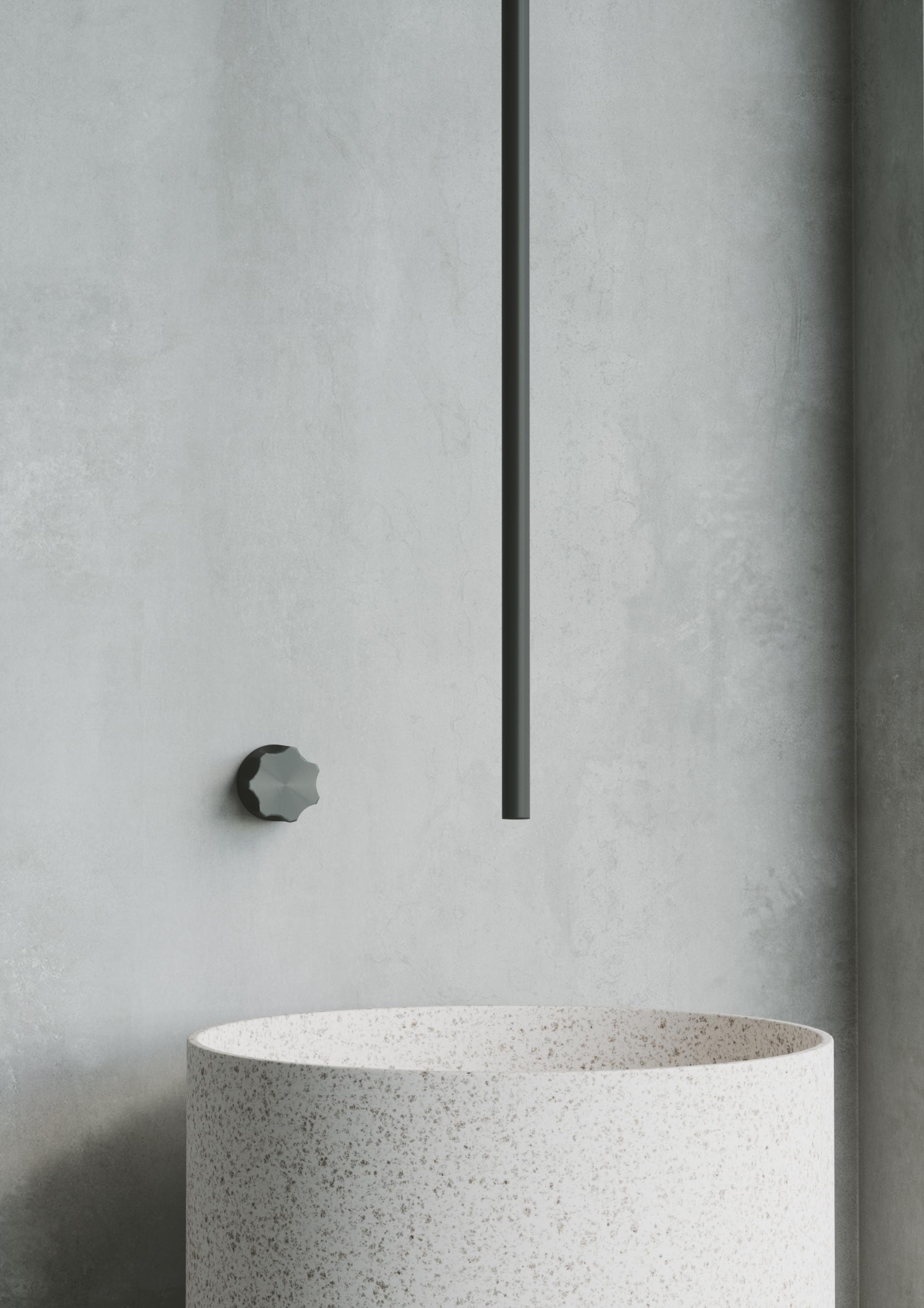 Minimalist bathroom setting featuring a round, speckled basin and sleek wall-mounted faucet designed by Quadro Design Italy.