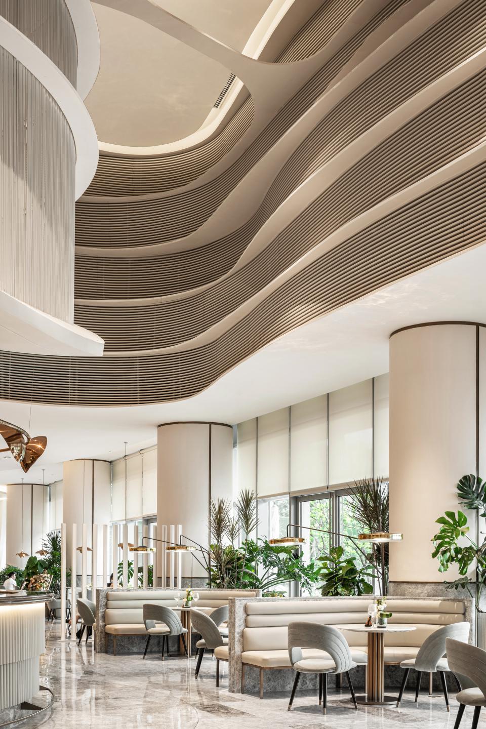 Elegant interior of a modern urban community centre featuring curved ceilings, greenery, and stylish seating arrangements.