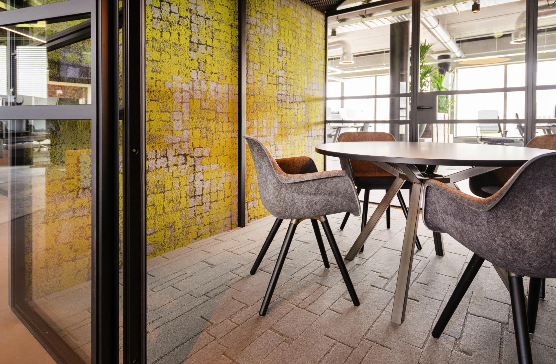 Modern meeting space at Vepa, featuring sustainable design elements, stylish chairs, and a vibrant yellow textured wall.