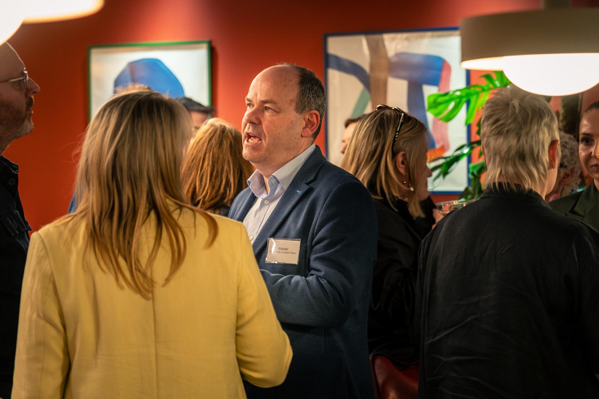 Networking event discussing Glasgow's property outlook, featuring professionals engaged in conversation in a vibrant setting.