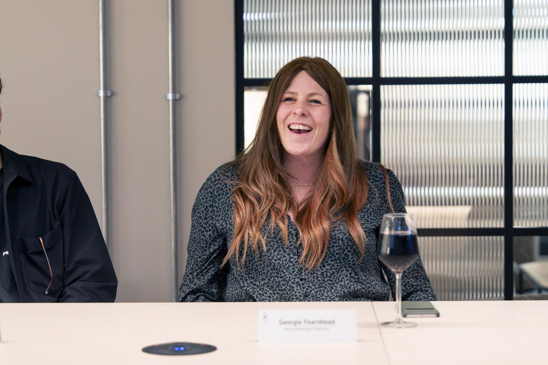 Participant laughing during a roundtable discussion on Manchester's residential property mix, with a glass of wine on the table.