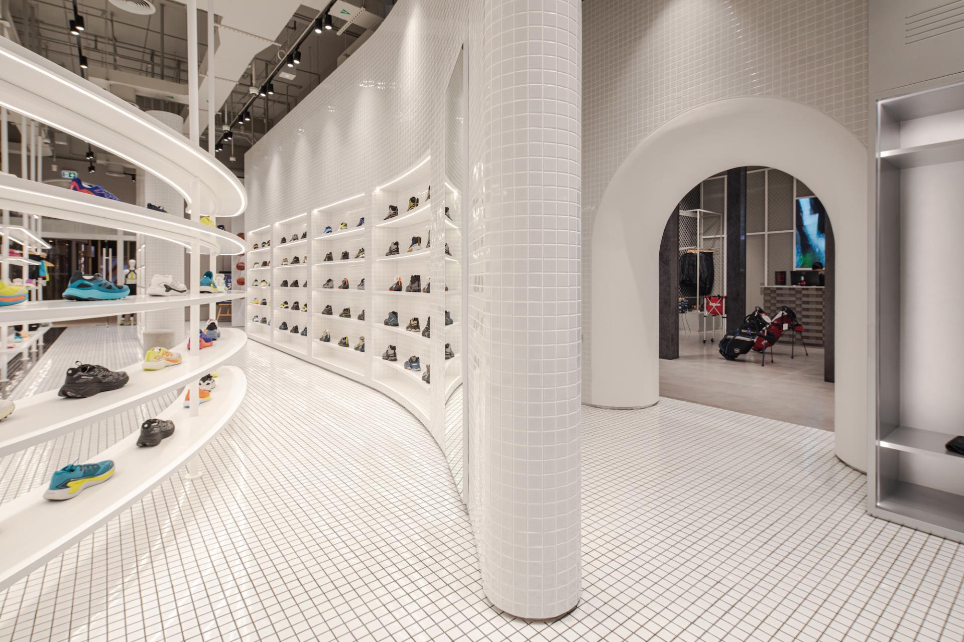 Modern retail space featuring interactive displays of vibrant activewear and footwear in a sleek, minimalist design.