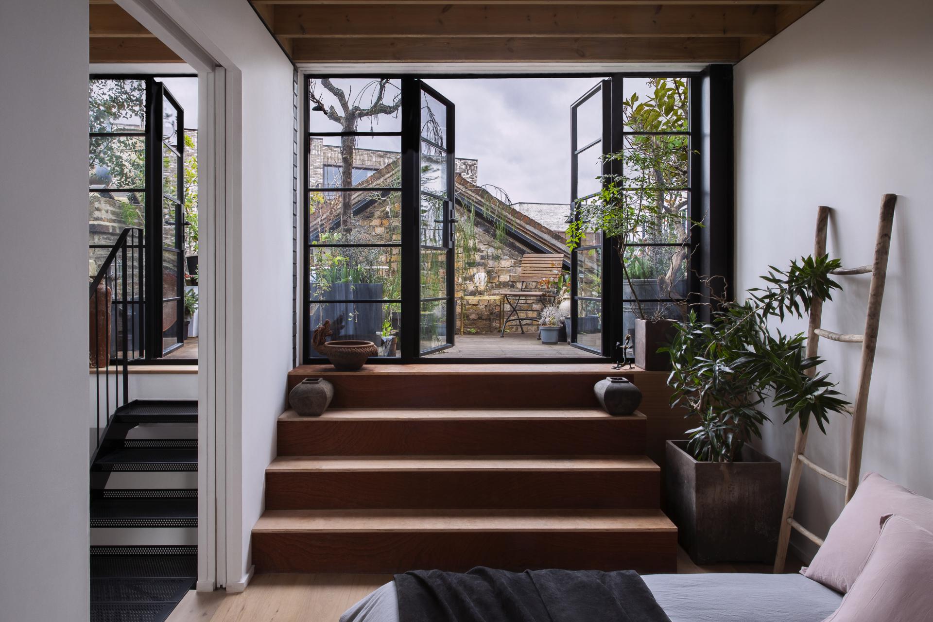 Stylish interior view showcasing open doors leading to a lush outdoor garden, emphasizing sustainable design principles.