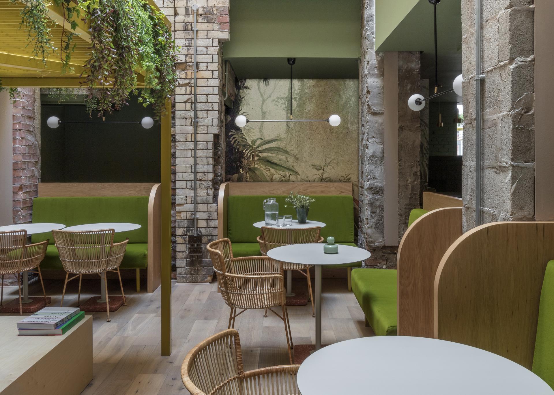 Cozy interior of Whitworth Locke aparthotel featuring green seating, wooden accents, and vintage brick walls, ideal for relaxation.