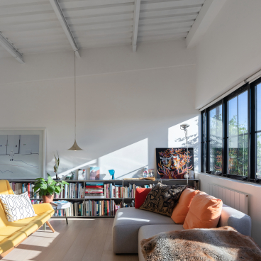 Stylish studio flat interior showcasing art deco design, bright natural light, and a cozy reading area with bookshelves.