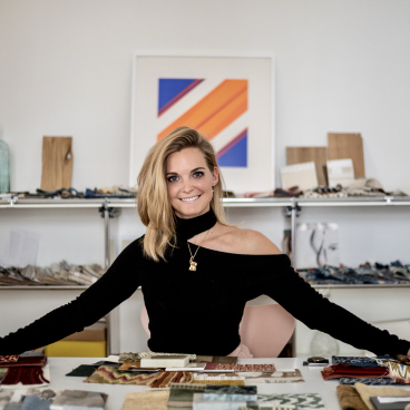 Theresa Obermoser showcases colorful fabric swatches in her interior design studio, highlighting her creative design process.
