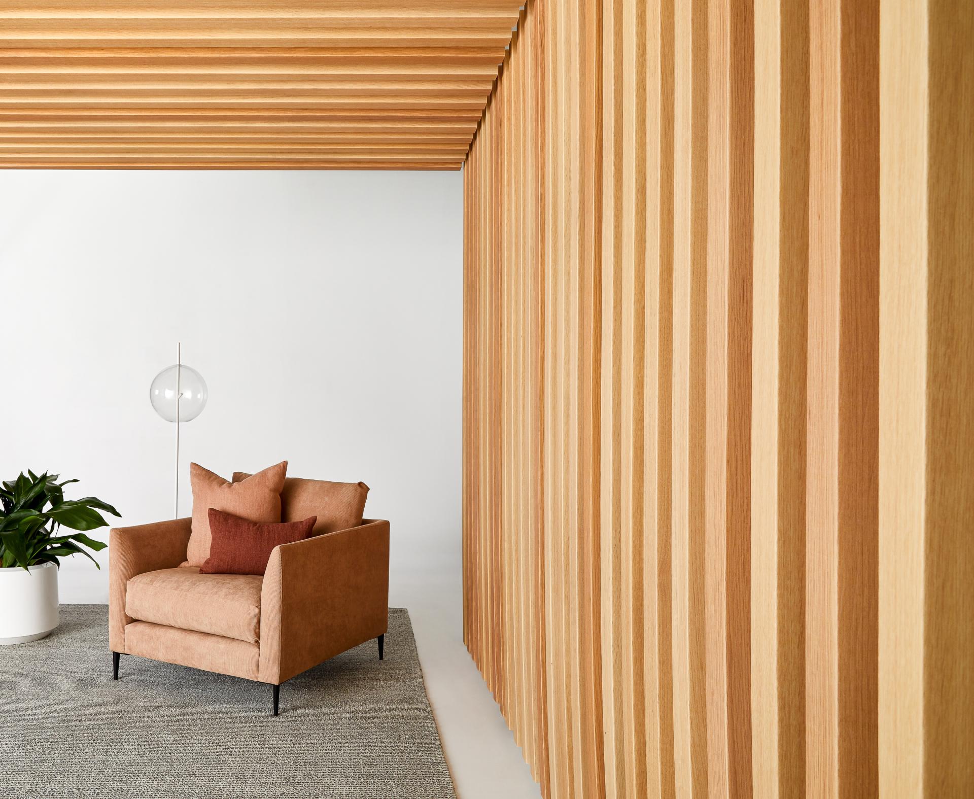 Stylish interior featuring acoustic timber paneling, a plush armchair, and a modern lamp, emphasizing acoustic design in contemporary spaces.