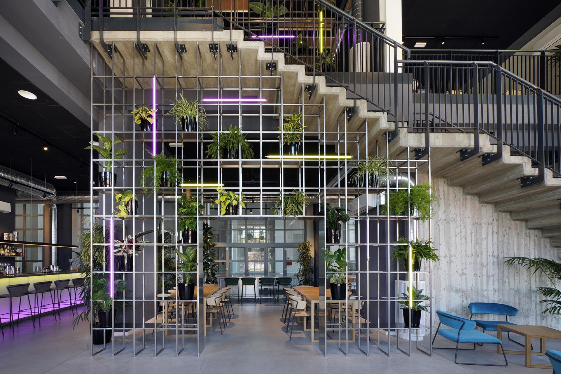 Redesigned former power plant interior featuring a modern café space with greenery and contemporary decor in Bergamo.