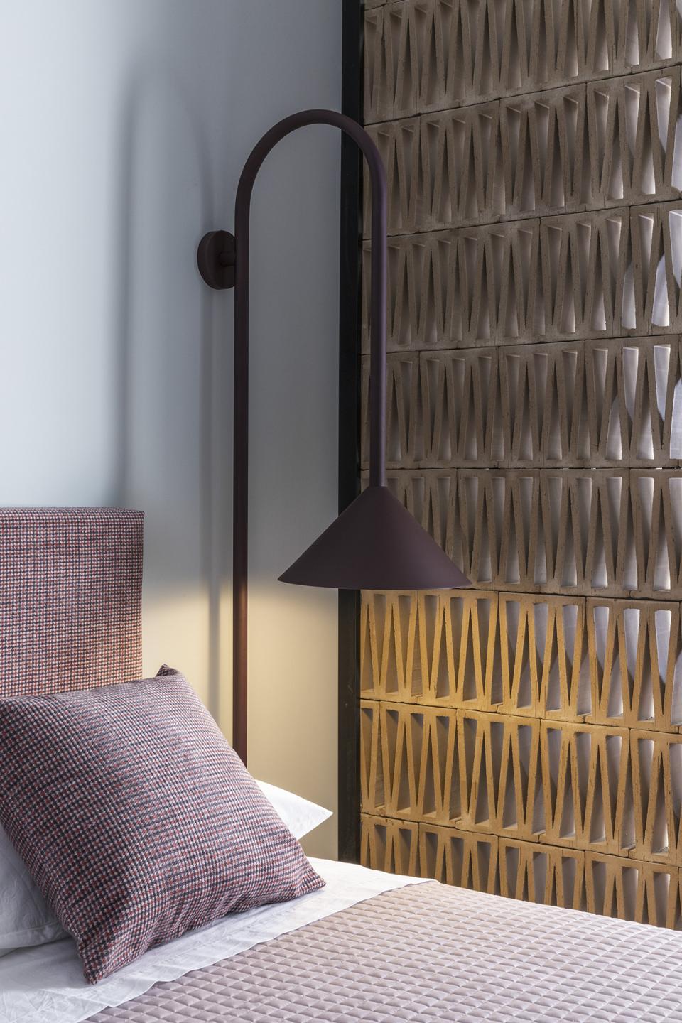 Stylish bedroom featuring a patterned headboard, modern light fixture, and textured wall in a Trastevere apartment.