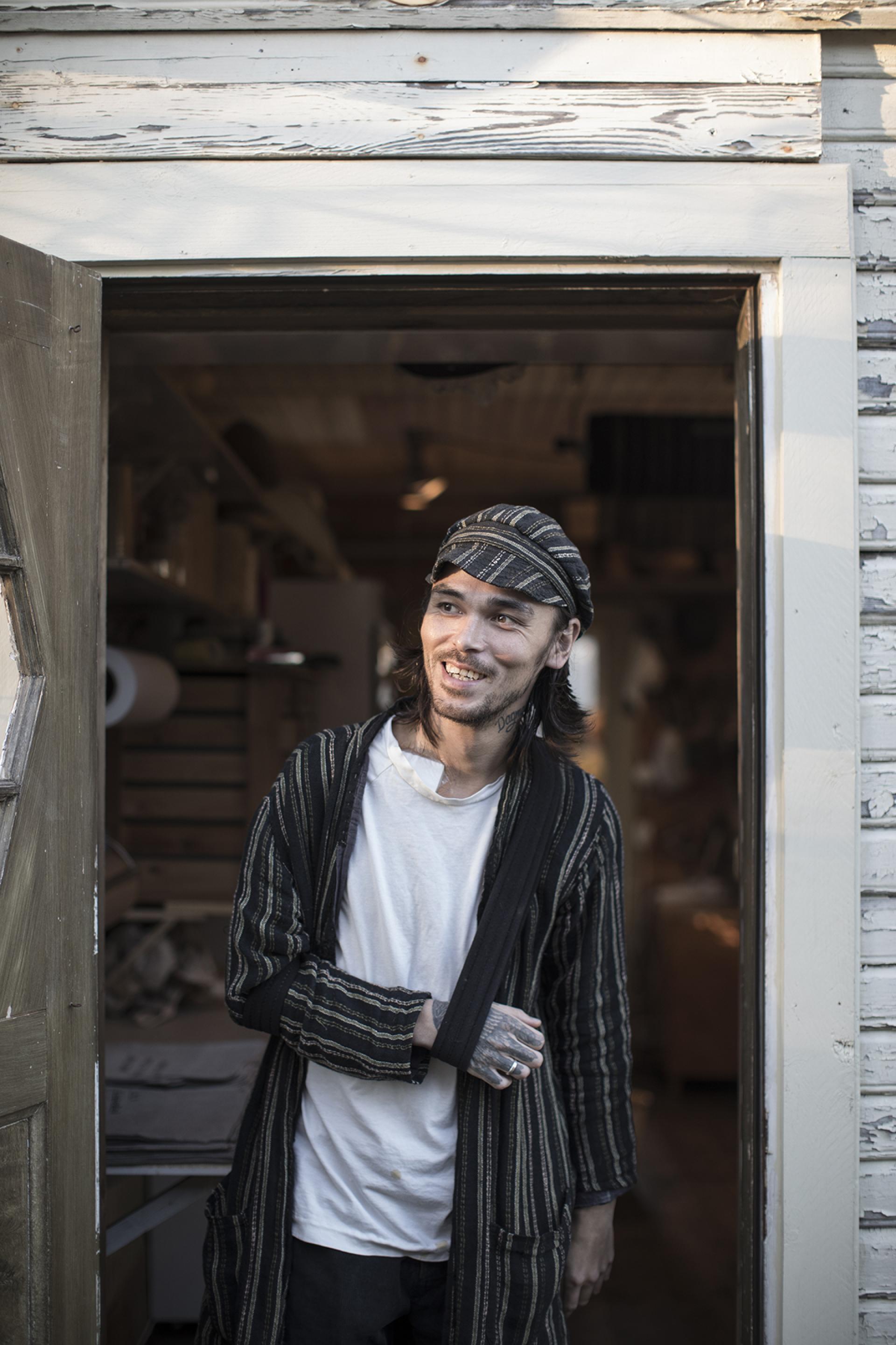 A hatmaker stands at the entrance of Horisaki workshop in Småland, Sweden, showcasing local craftsmanship.