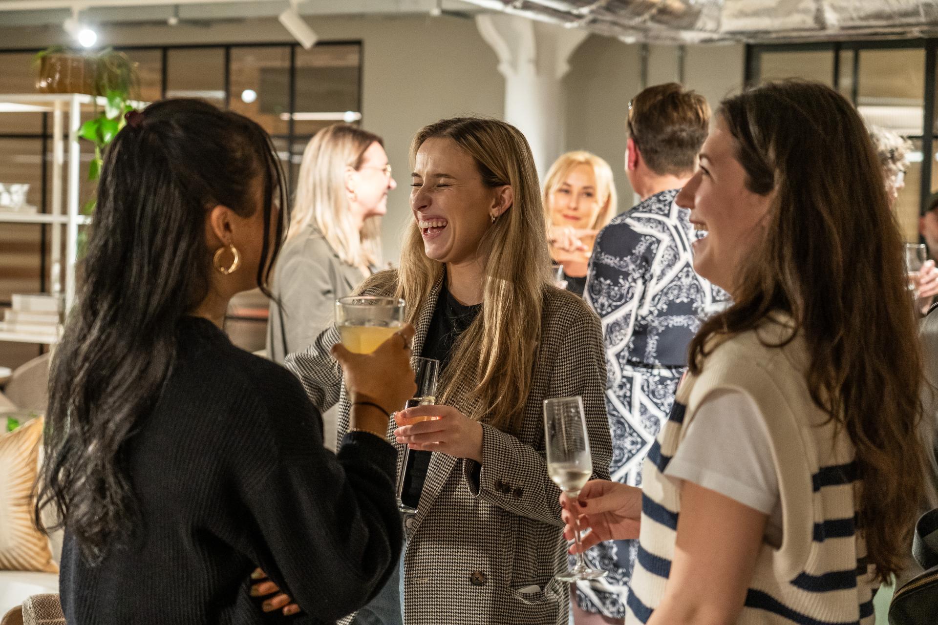 Networking event attendees enjoying conversations and drinks, reflecting modern workplace social interactions and collaboration.