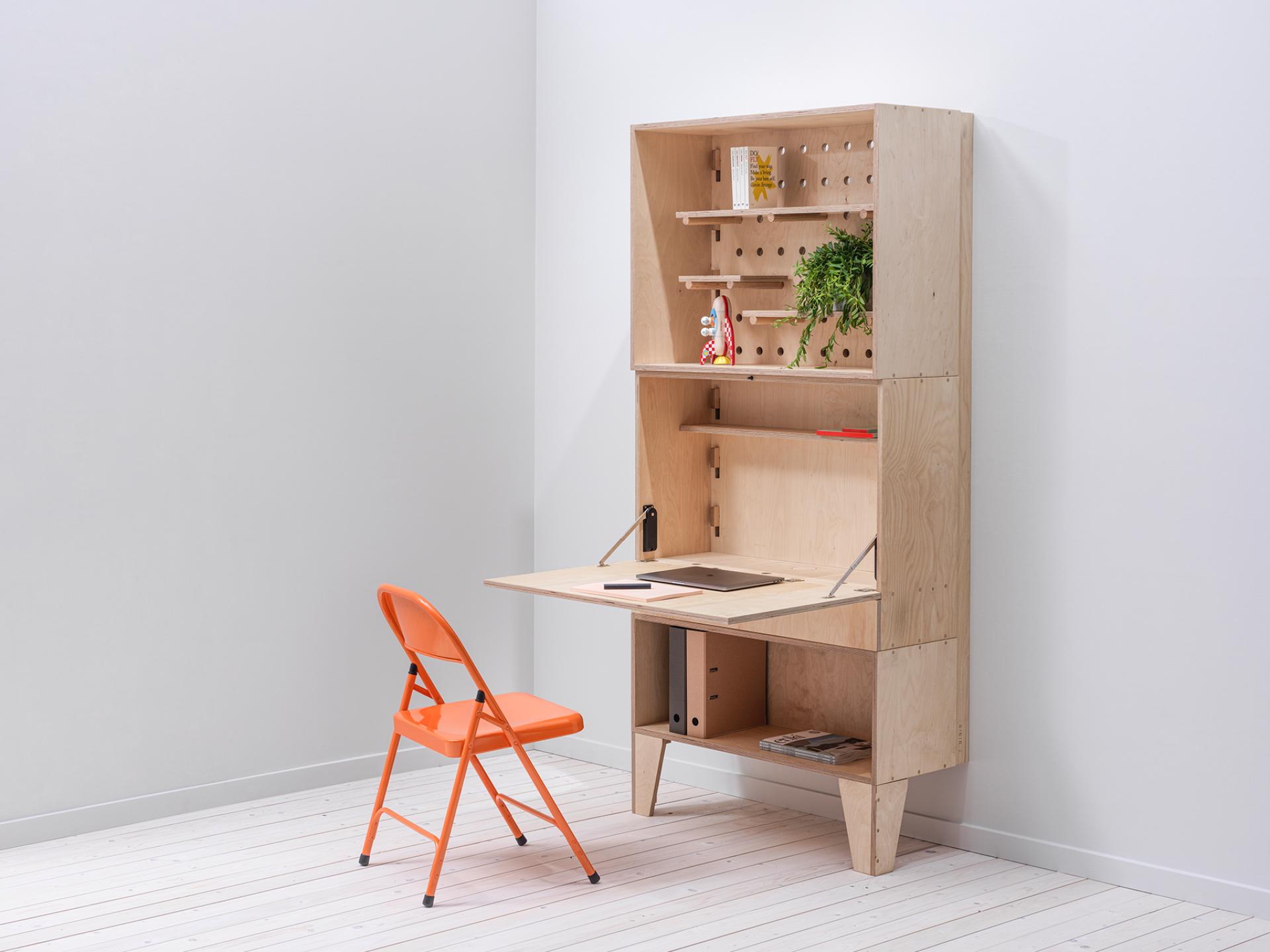 Bespoke modular workspace in Manchester featuring a wooden desk, shelving, and an orange folding chair.