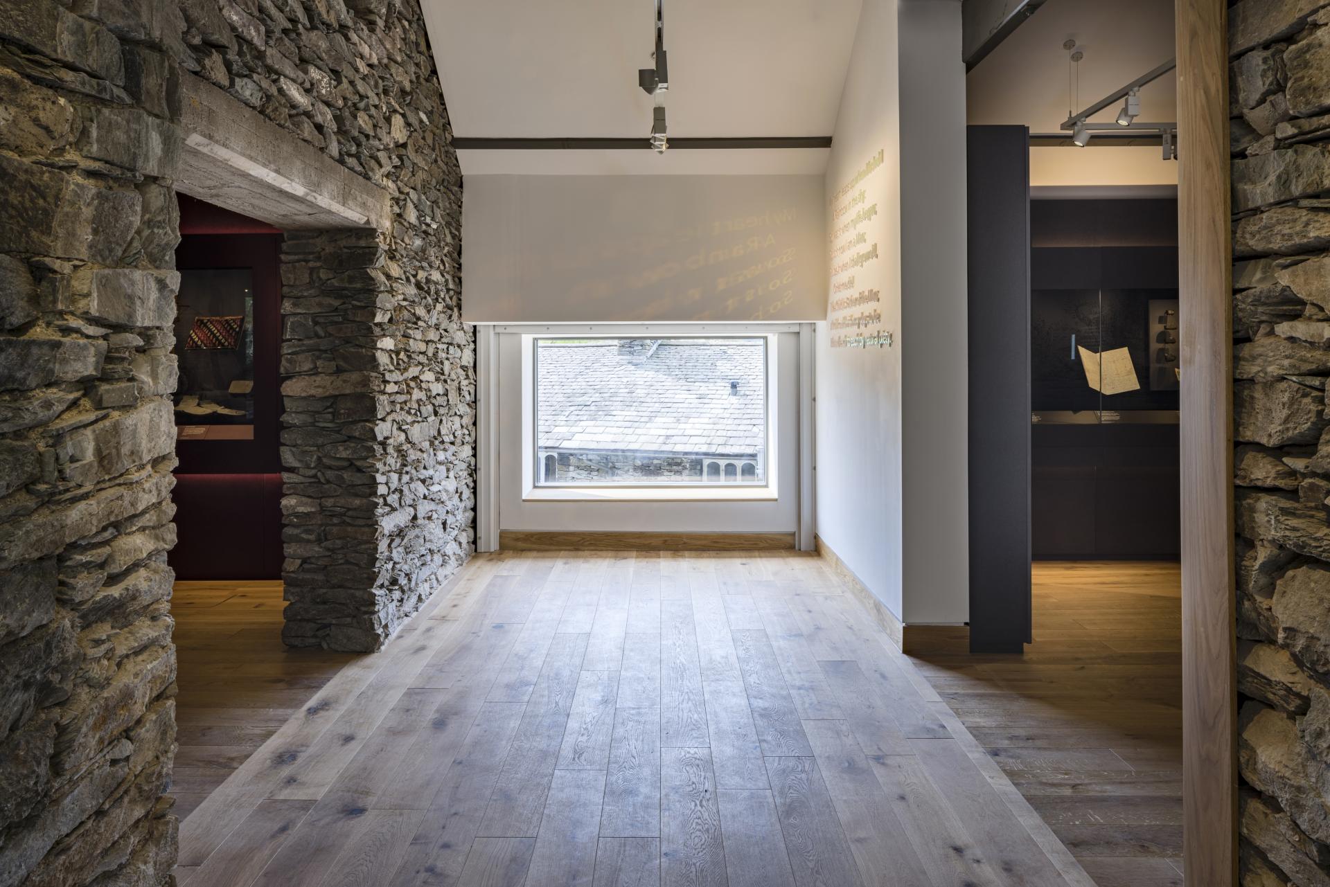 Modern gallery space at The Museum at Wordsworth Grasmere, featuring stone walls, wooden floors, and natural light.