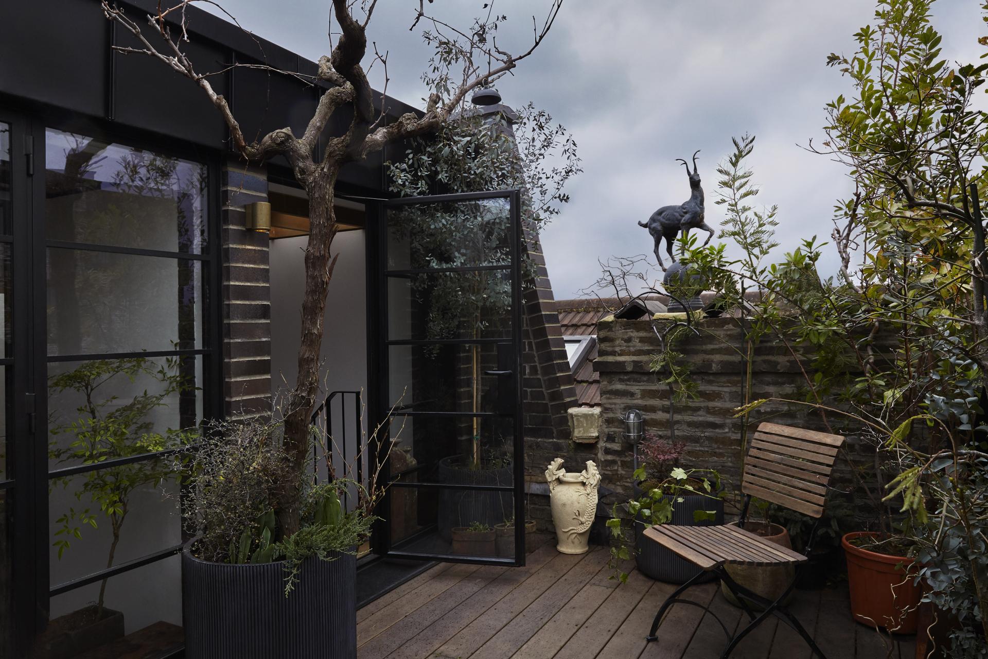 Stylish urban terrace featuring plants, modern design elements, and unique sculptures, highlighting sustainable architecture in East London.