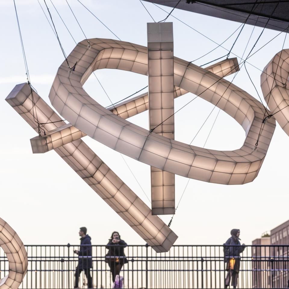 Giant sculptural lights by Studio Mieke Meijer illuminate Coal Drops Yard, featuring unique geometric designs against a twilight sky.