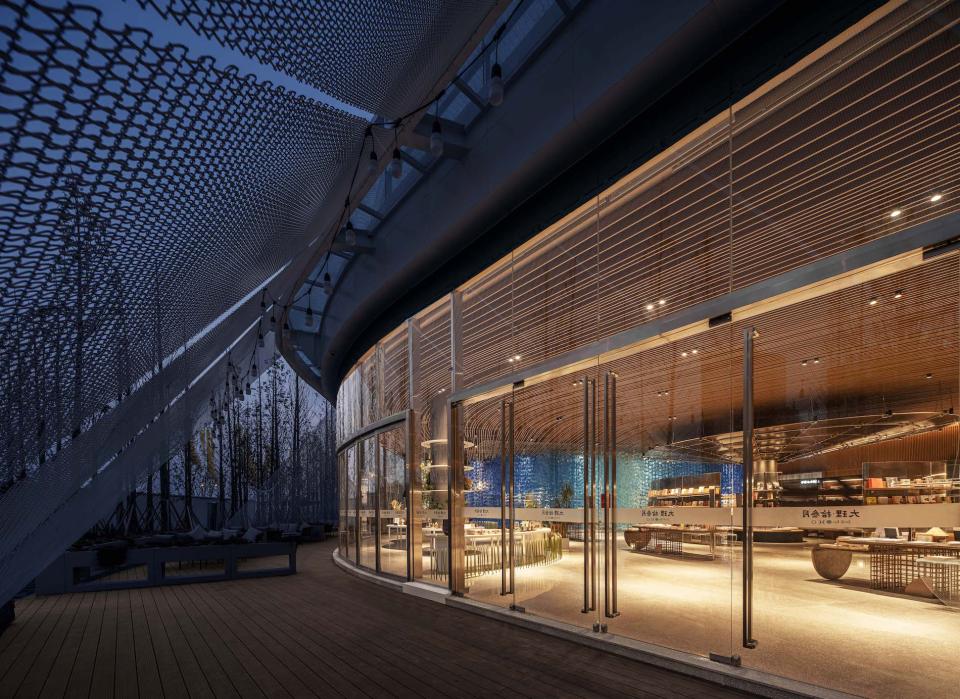 Sleek entrance of The Leas exhibition hall in Dali, showcasing modern architecture amidst lush greenery at dusk.