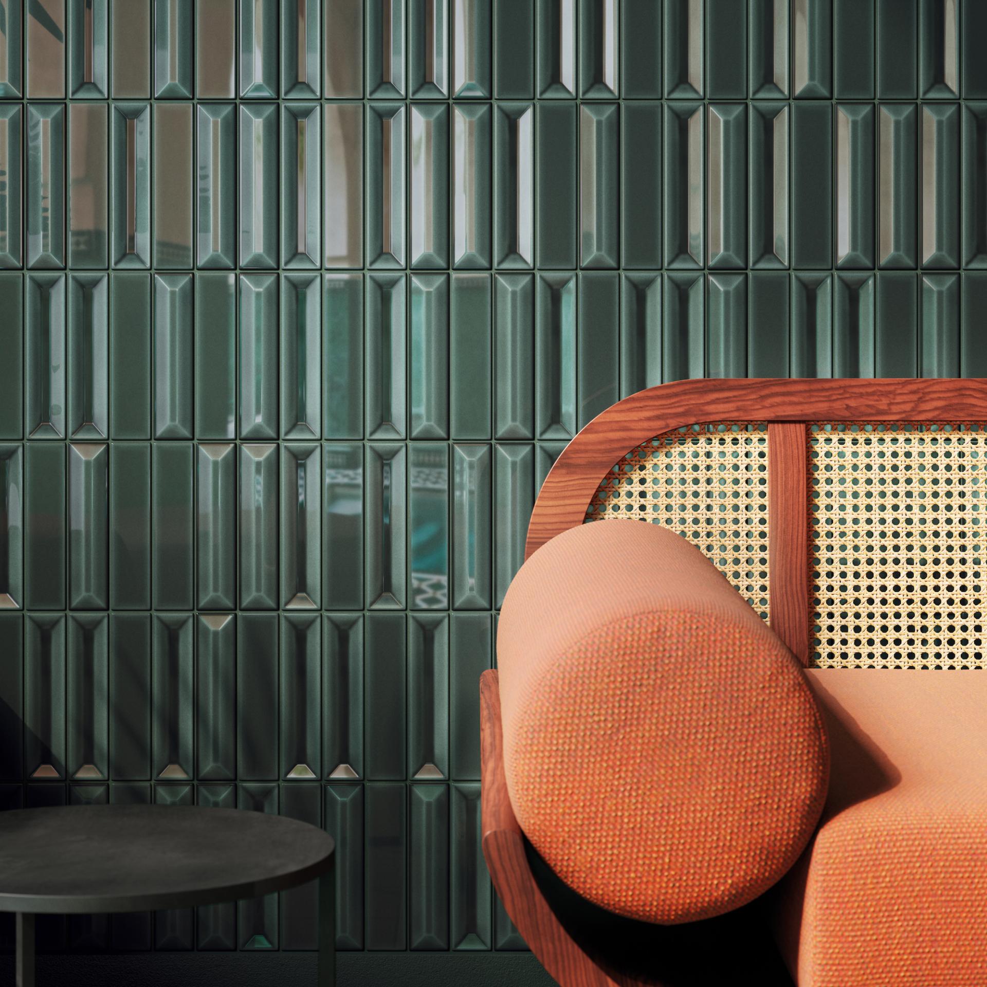 Elegant green tiled wall with a modern orange sofa featuring a round cushion, showcasing contemporary interior design.
