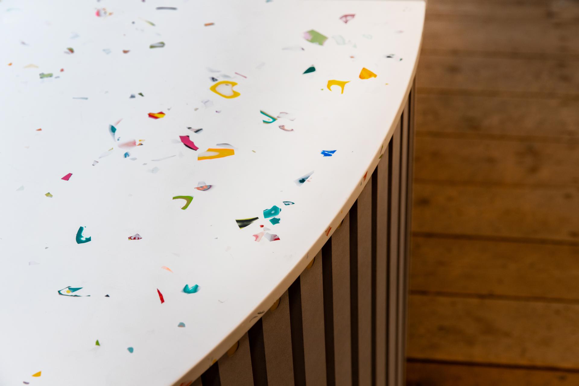 Colorful fragments scattered on a white, curved surface representing innovative surface design by Mirrl in Glasgow.