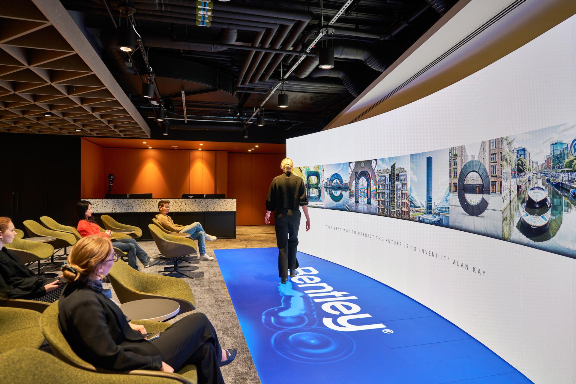 Innovative workspace design for Bentley Systems featuring a digital display and comfortable seating for collaboration.