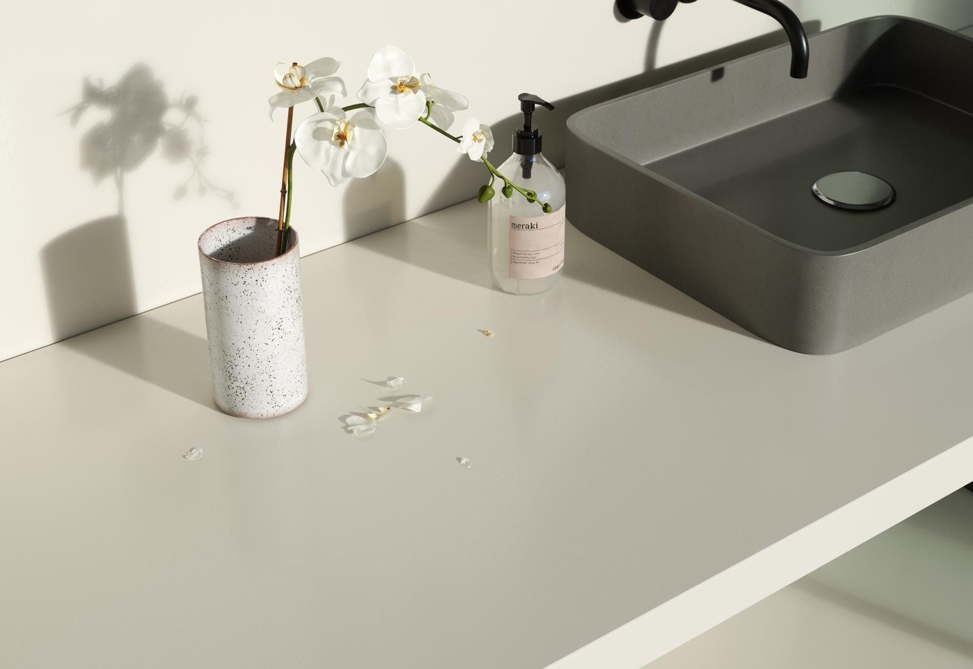 Elegant countertop with Silestone surface, featuring a gray sink, a speckled vase with orchids, and a soap dispenser.