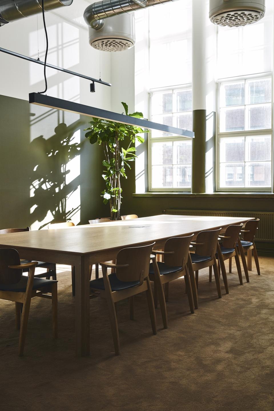 Stylish meeting room in a refurbished bread factory, featuring a large wooden table, chairs, and natural light.