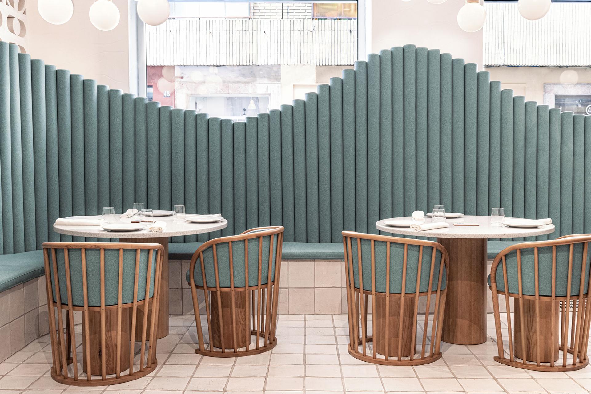 Stylish restaurant interior featuring curved upholstered seating and modern wooden tables at La Sastrería in Valencia.