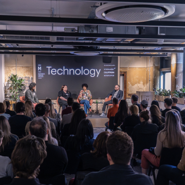 Panel discussion on technology at Material Source Studio, featuring speakers and an engaged audience in a modern setting.