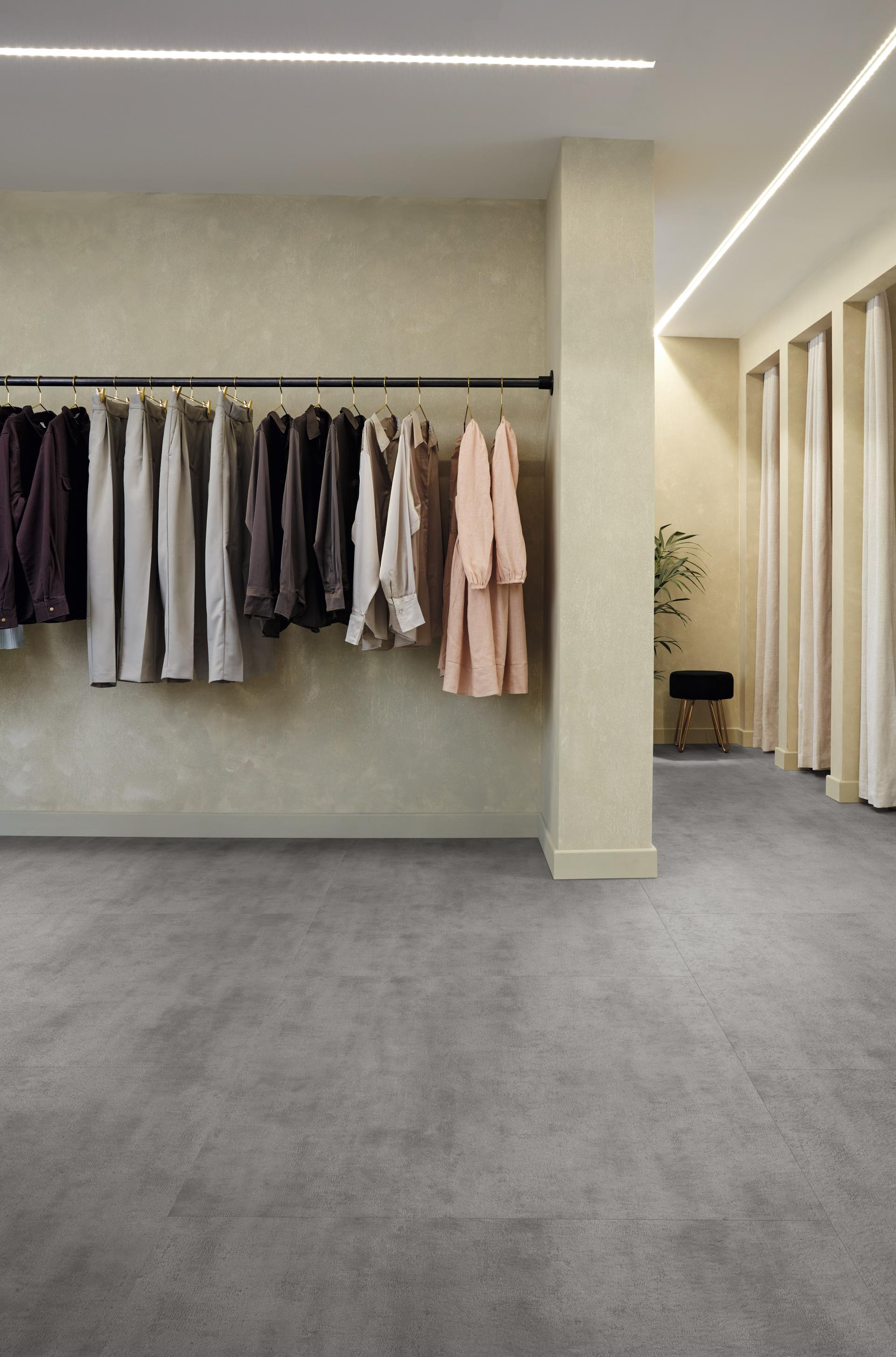 Stylish interior featuring Karndean Designflooring's extra-large concrete tiles, showcasing a modern retail space with hanging clothing.
