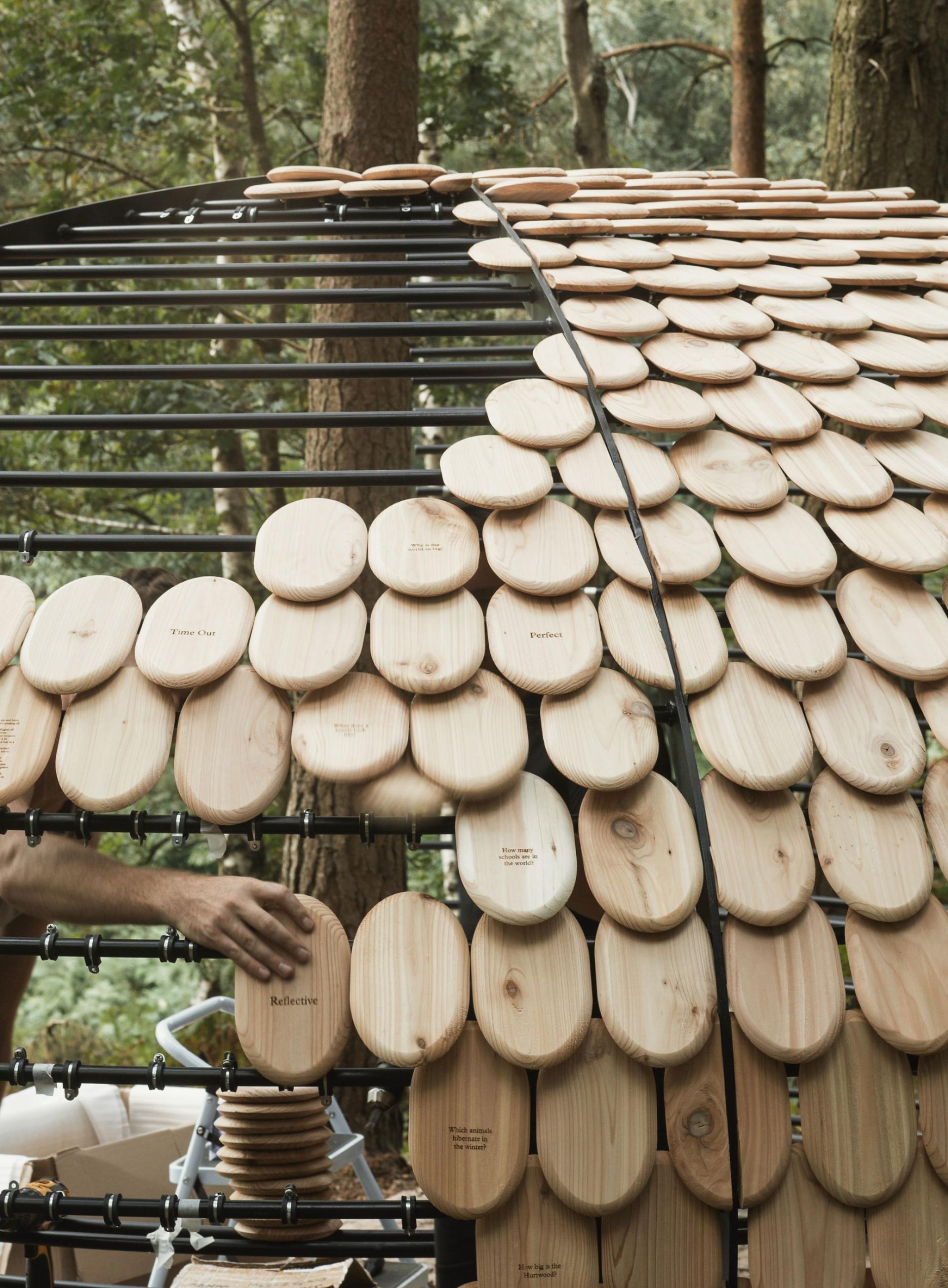 Organic pavilion by Giles Miller in Surrey's Winterfold Forest, featuring wooden panels and nature-inspired architecture.