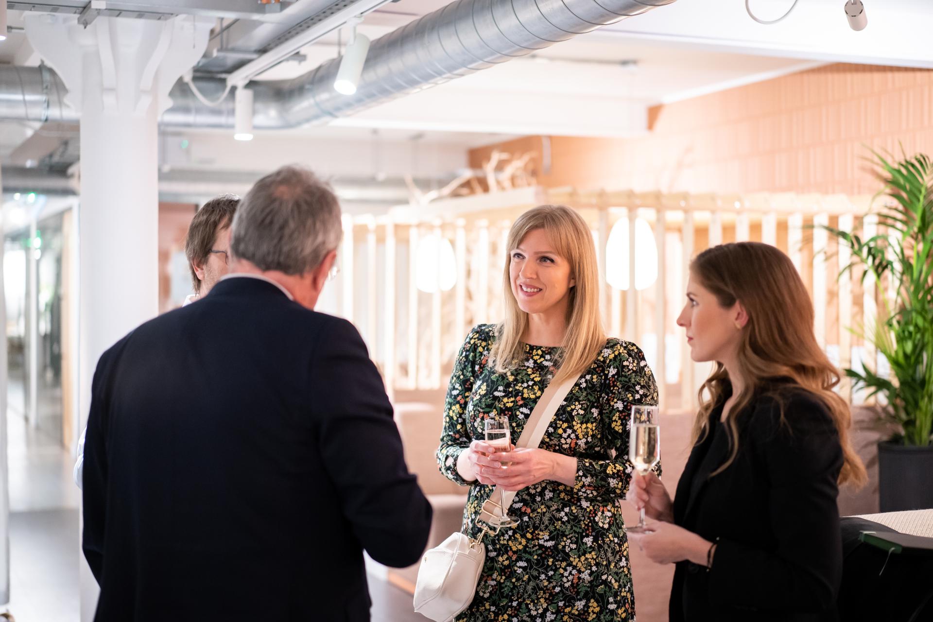Networking event attendees engaging in conversation, highlighting themes of sustainability and collaboration in a modern setting.
