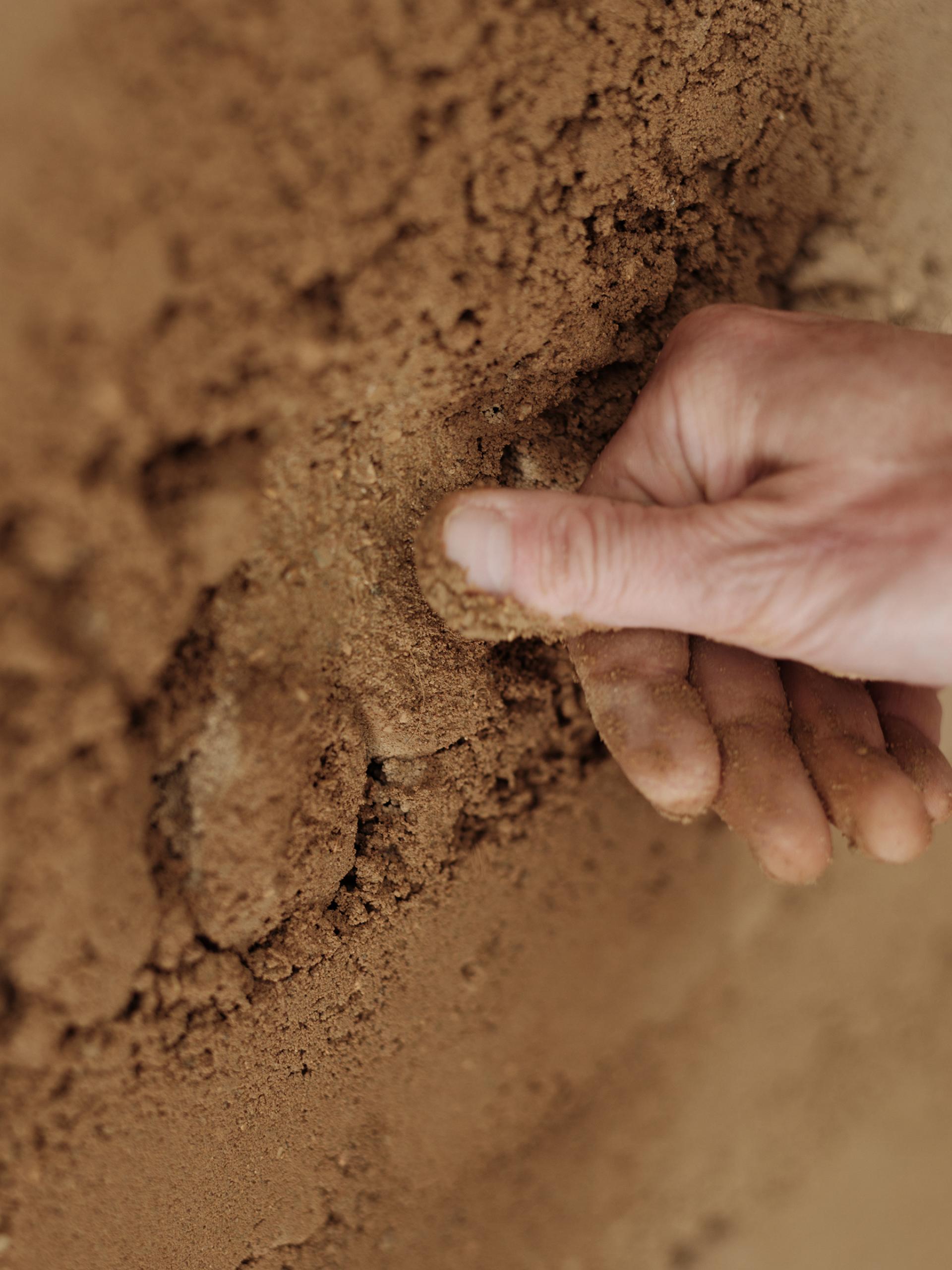 Hand compacting a textured clay wall finish, showcasing Clayworks' sustainable rammed earth aesthetic.