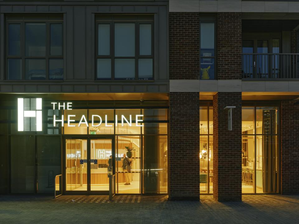 The illuminated entrance of The Headline in Leeds, showcasing modern residential design and welcoming amenity spaces.