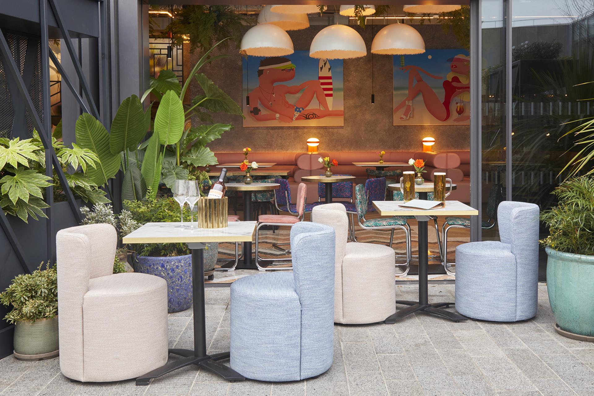 Vibrant outdoor seating area at Bondi Green featuring colorful chairs, tropical plants, and artistic decor, inspired by Miami.