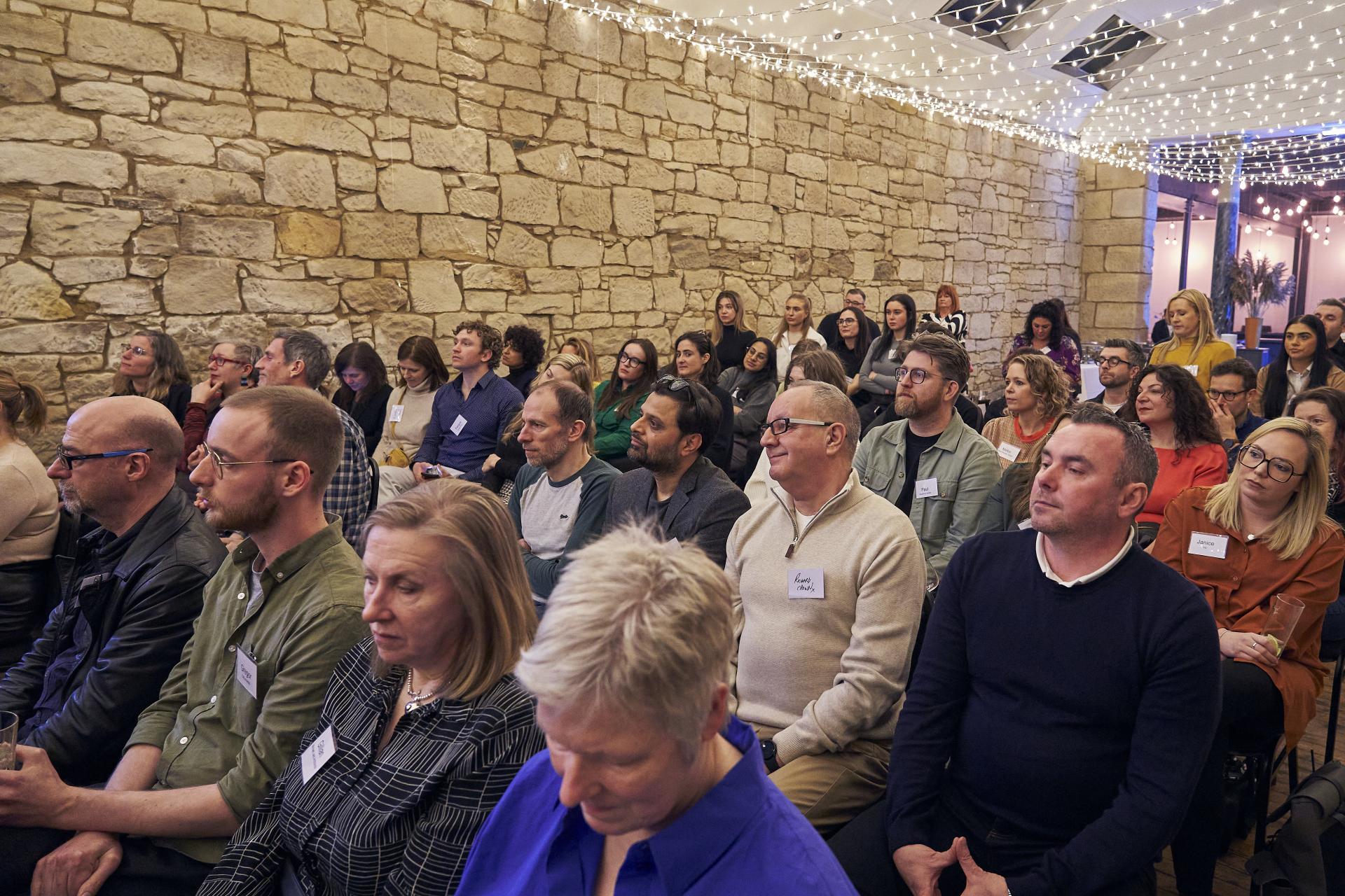 Attendees engaged in a sustainability discussion at Material Source Studio Glasgow, surrounded by a cozy, illuminated atmosphere.