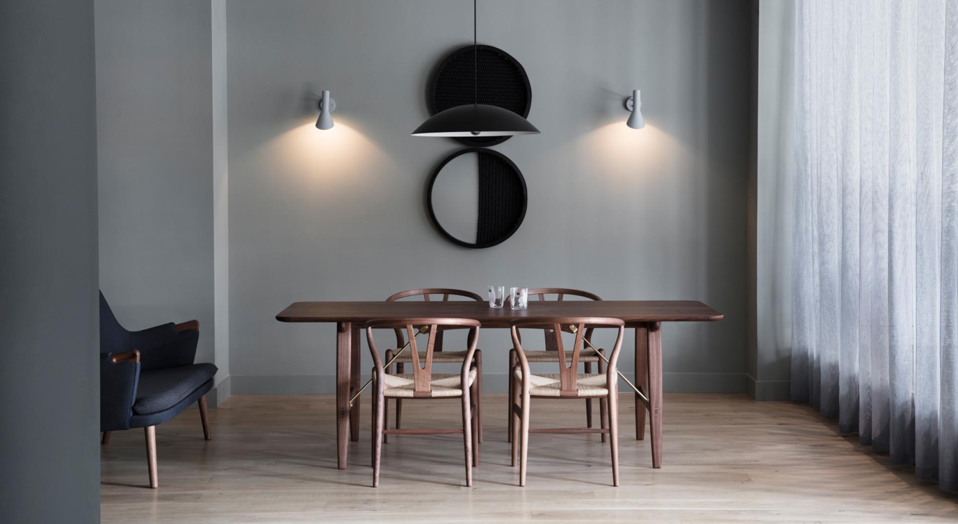 Elegant dining area featuring a wooden table, woven chairs, and stylish lighting in Carl Hansen & Son's London store.