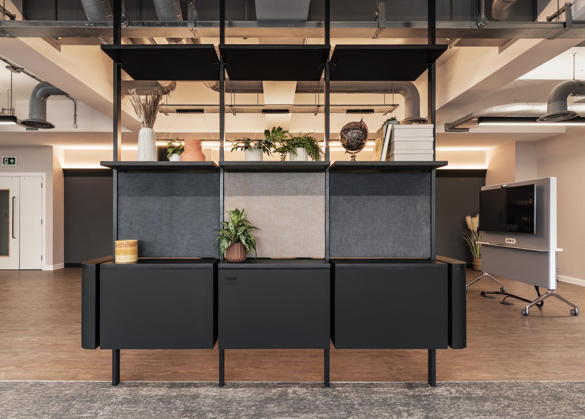 Modern office workspace featuring sleek furniture, decorative plants, and unique shelving, designed for Tosca Debt Capital in Manchester.