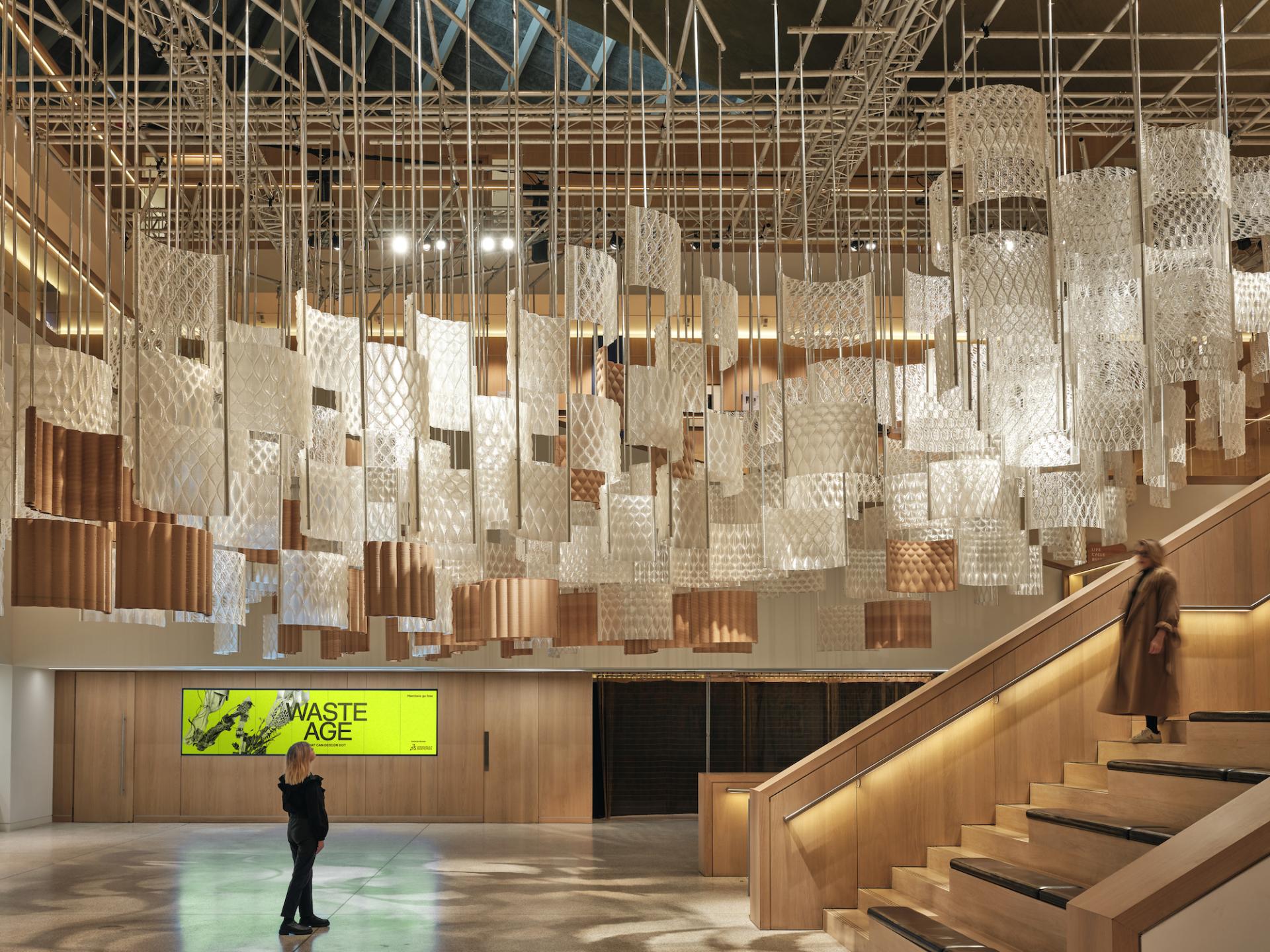 Hanging installation made of translucent materials at the Design Museum, featuring visitors during COP26's Aurora exhibit.