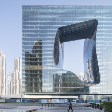 Modern architectural masterpiece by Zaha Hadid Architects, showcasing unique facades and reflections in a vibrant urban setting.