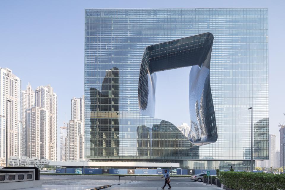 Modern architectural masterpiece by Zaha Hadid Architects, showcasing unique facades and reflections in a vibrant urban setting.