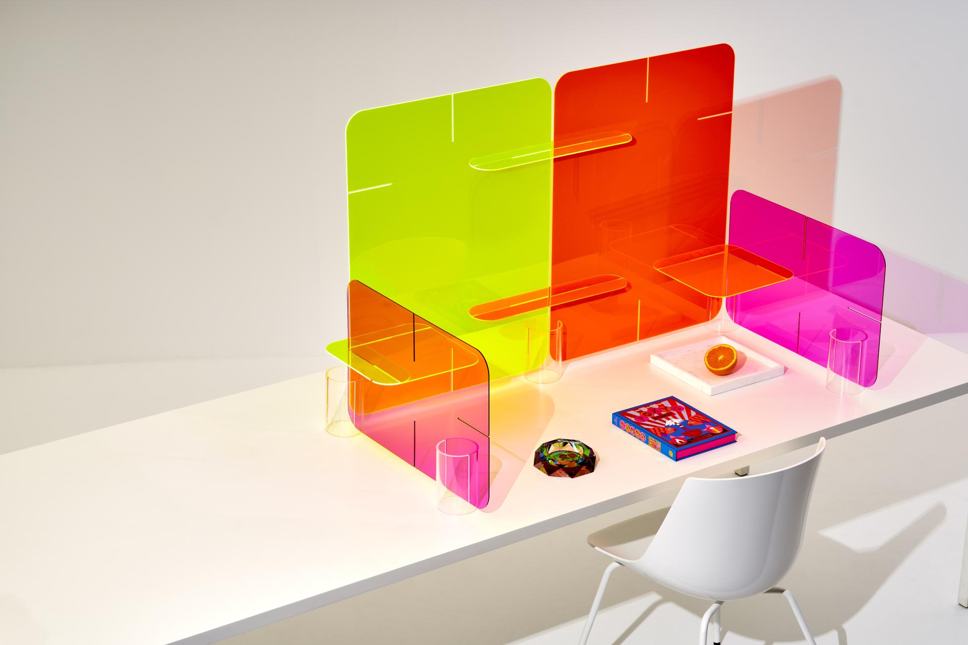 Vibrant acrylic partitions on a modern desk, showcasing Zahava Elenberg's innovative Clikclax design for collaborative workspaces.